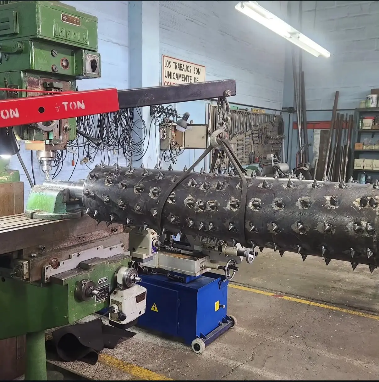 Rolo de púas en fresadora — Agujereado y posicionado de púas sobre el rolo, con la pieza sostenida por grúa.